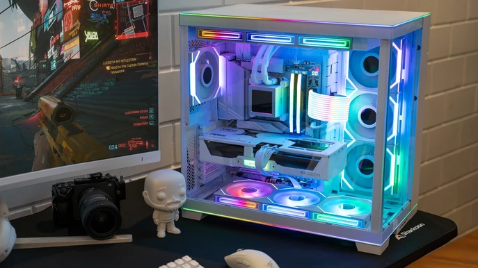 PC ALTERNATE Pure Lian Li blanc avec éclairage RGB complet à côté d'un moniteur gaming