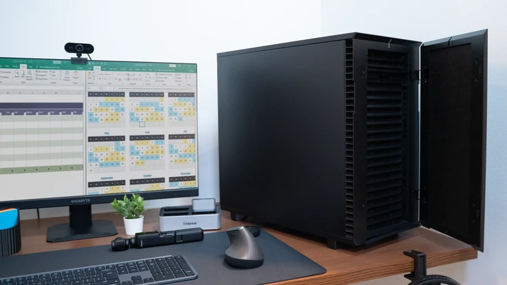 ALTERNATE Workstation Pro à côté d'un moniteur avec tableurs, installation de bureau