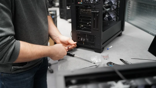 Technicien ALTERNATE assemblant un PC de bureau avec un tournevis