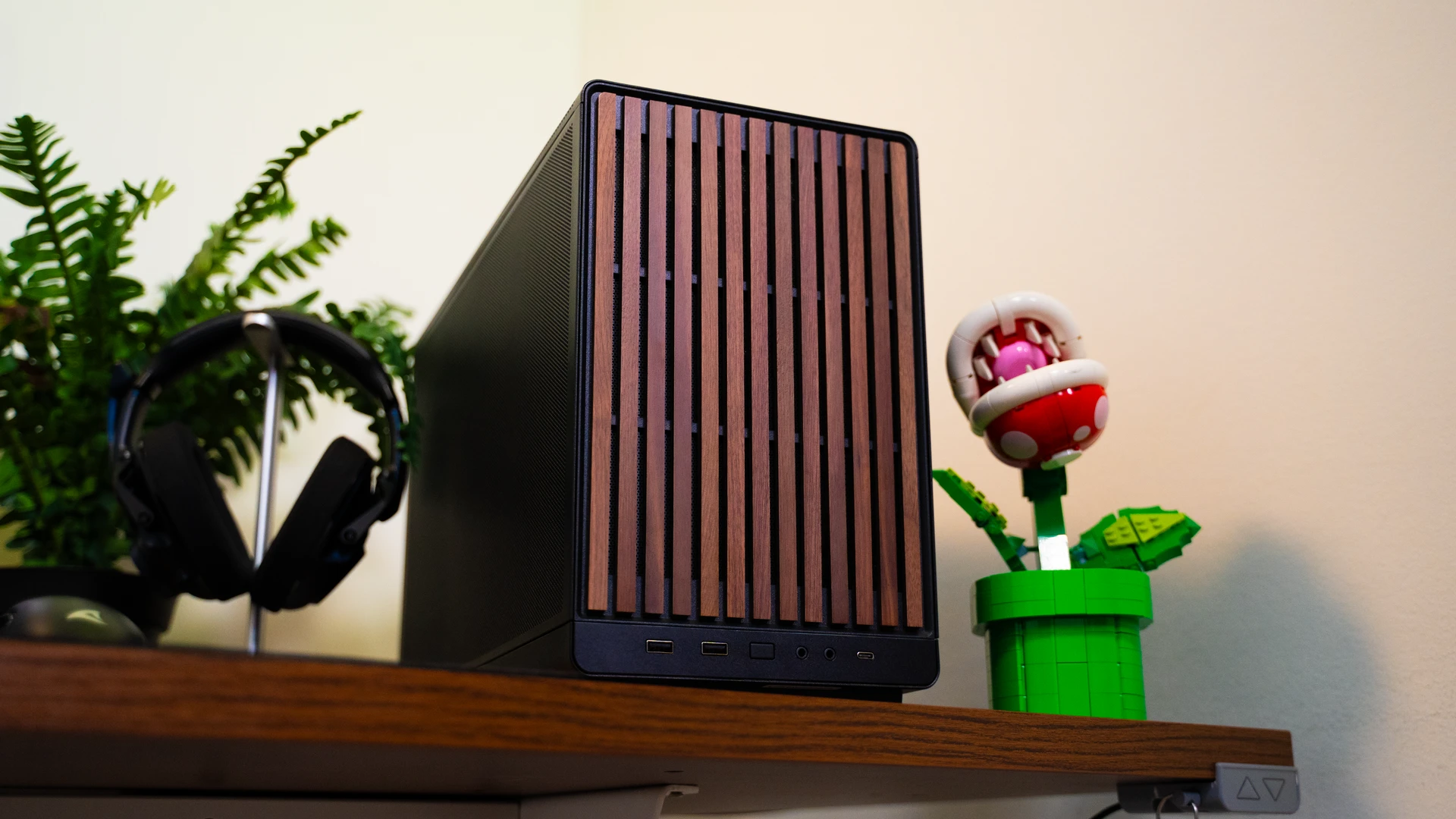 PC compact noir avec panneau frontal en bois à côté d'un moniteur gaming